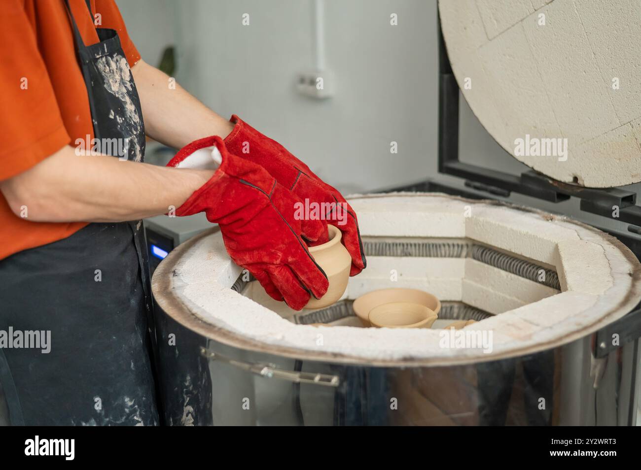 Close-up of a man's hands loading ceramics into a special kiln Stock ...