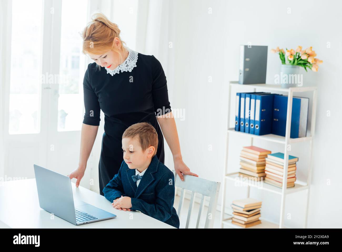 Teacher and boy studying at a desk with a laptop Stock Photo - Alamy