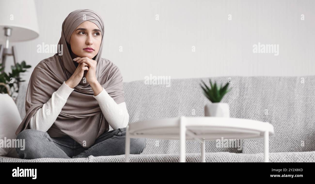 Thoughtful unhappy arabic woman in hijab sitting on couch at home Stock ...