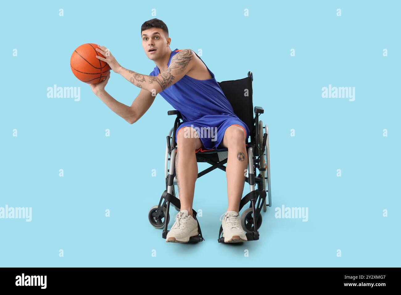 Male basketball player in wheelchair with ball on blue background Stock Photo