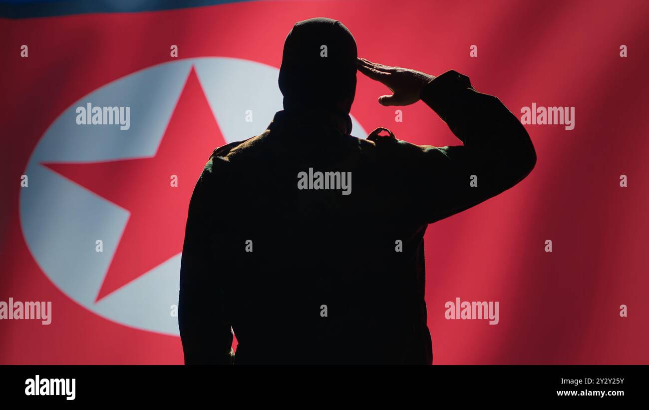 Conscript doing saluting hand gesture towards North Korea flag in command center, showing respect. Military unit in uniform serving in Korean Peoples Army, doing honoring gesturing, camera A Stock Photo