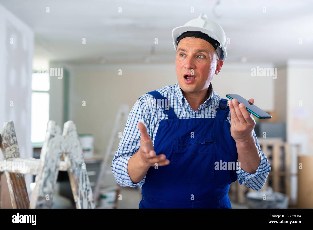 Foreman using smartphone, recording voice message Stock Photo