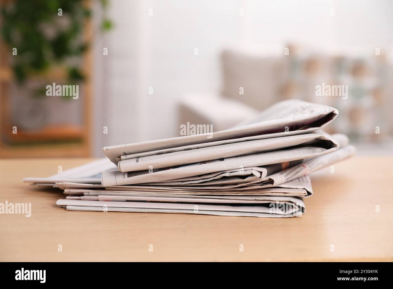 Stack of newspapers in different languages on table indoors Stock Photo