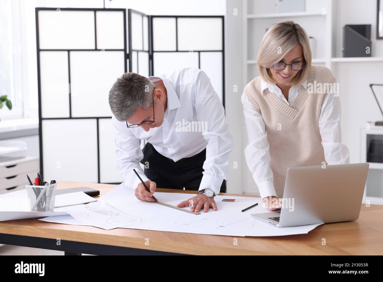 Architects making engineering drawing at wooden table in office Stock Photo