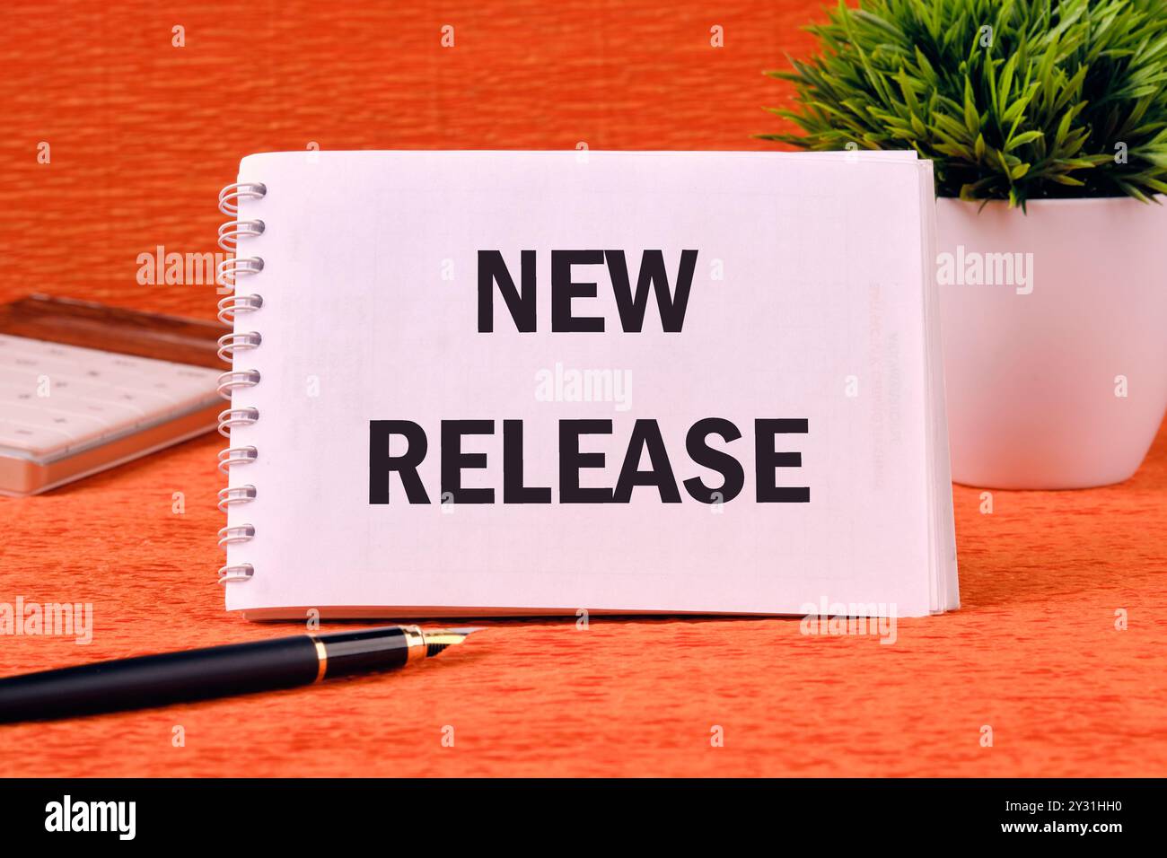Text NEW RELEASE on a blank notepad page on an orange back Stock Photo