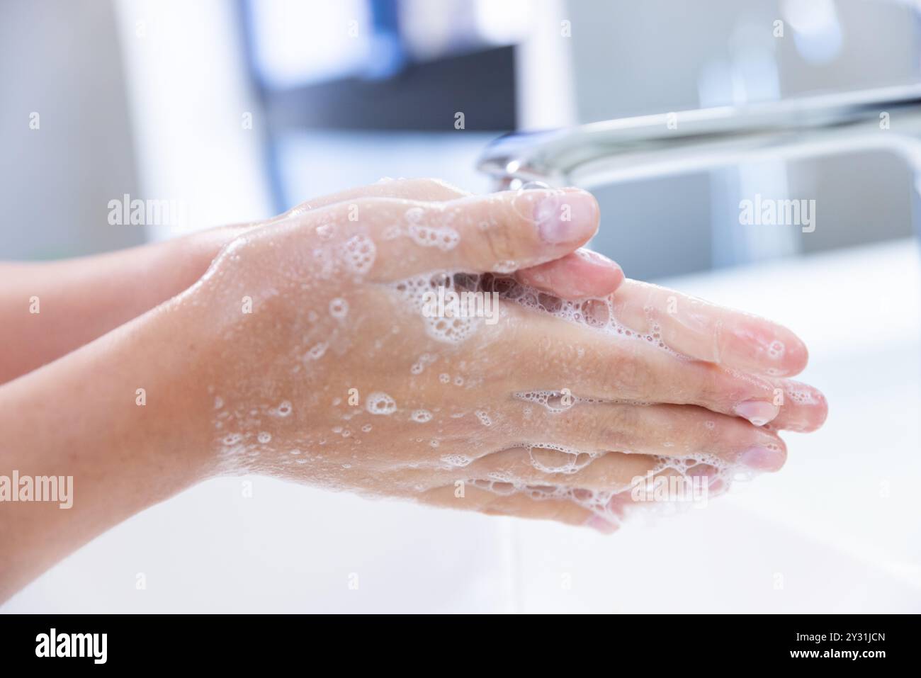 At home, Woman washing hands with soap and water, maintaining hygiene in spa setting Stock Photo