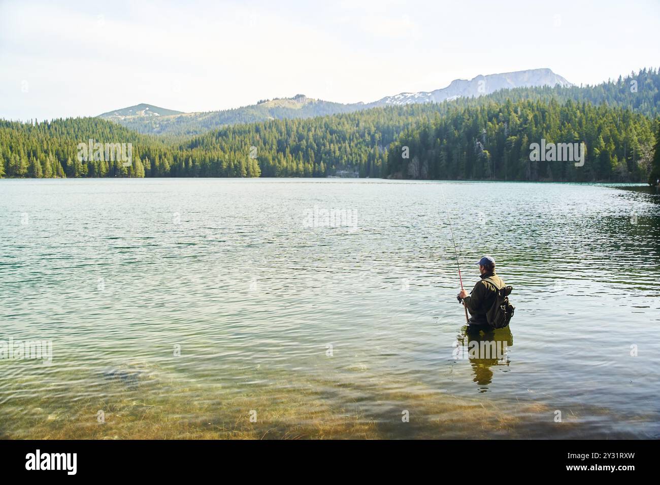 Fisher man stands in the water and catch fish in the lake on a ...