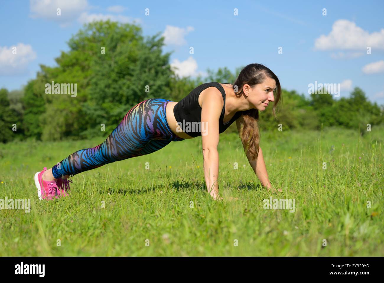 Woman doing push-ups in a meadow Stock Photo