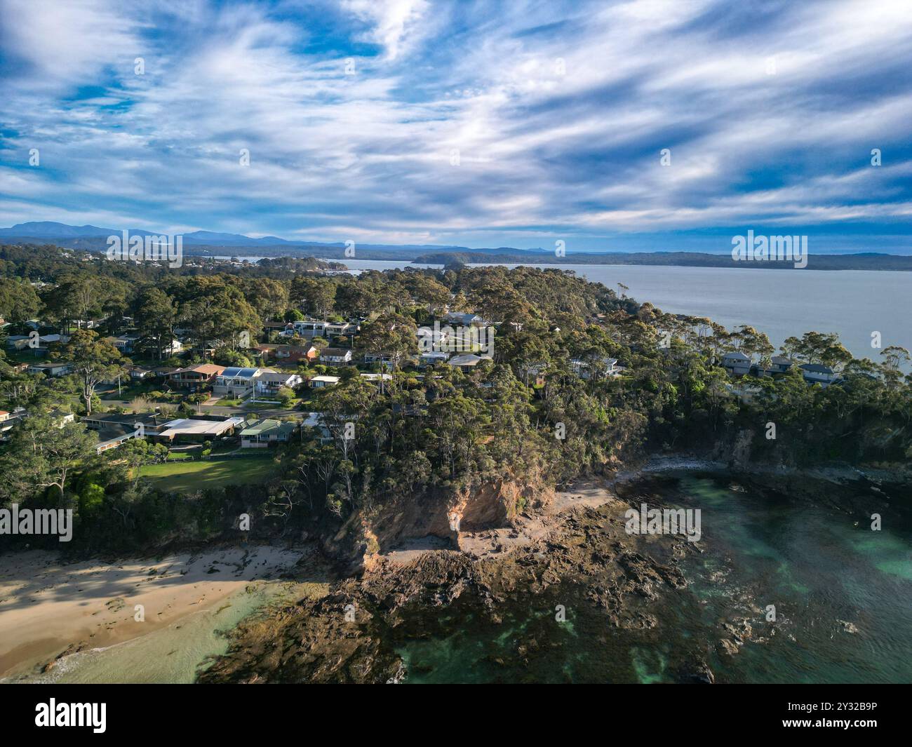 Aerial view of a coastal town with lush greenery, houses, and rocky ...
