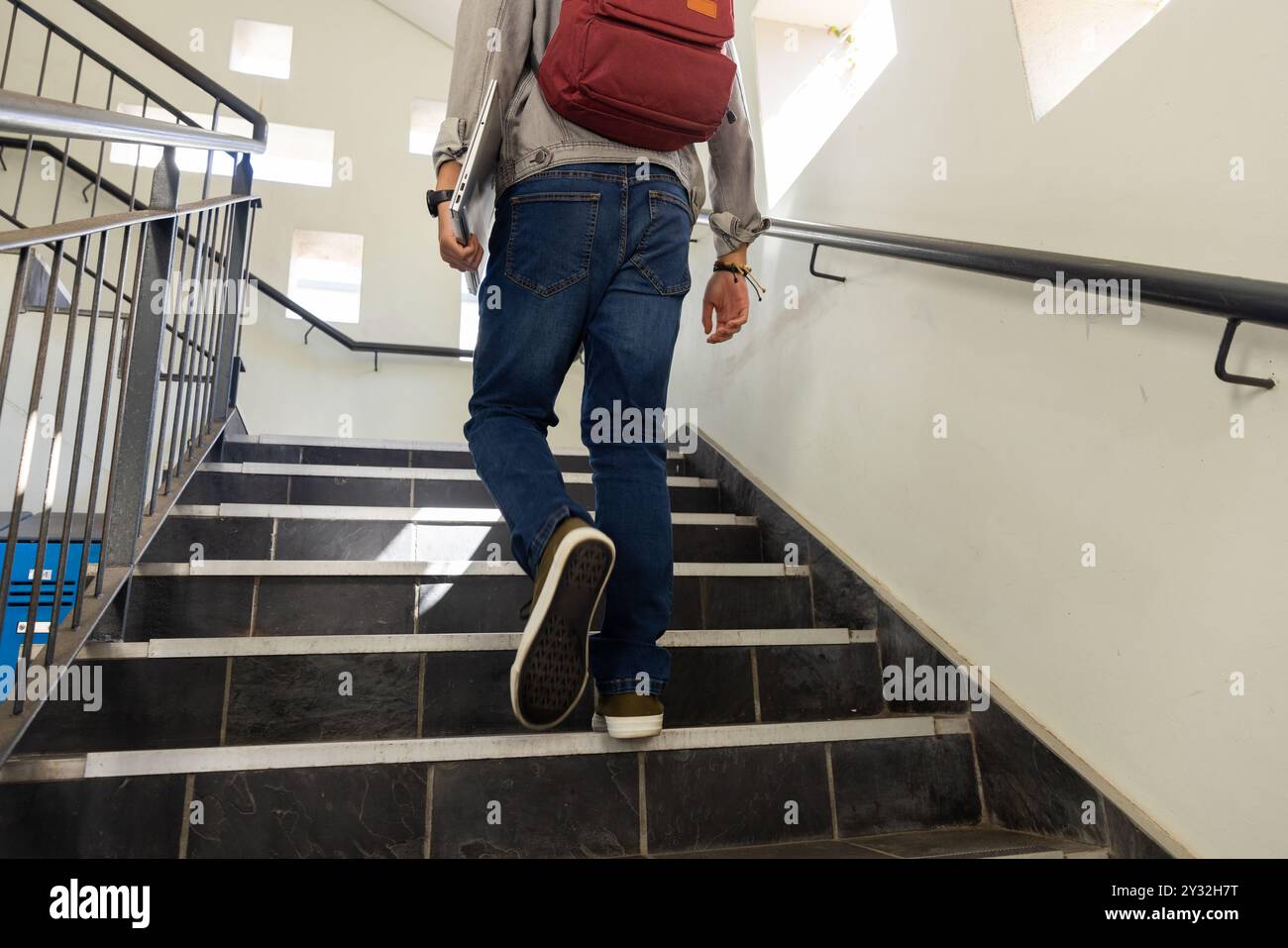 Walking up stairs, asian teenage boy with red backpack heading to class ...
