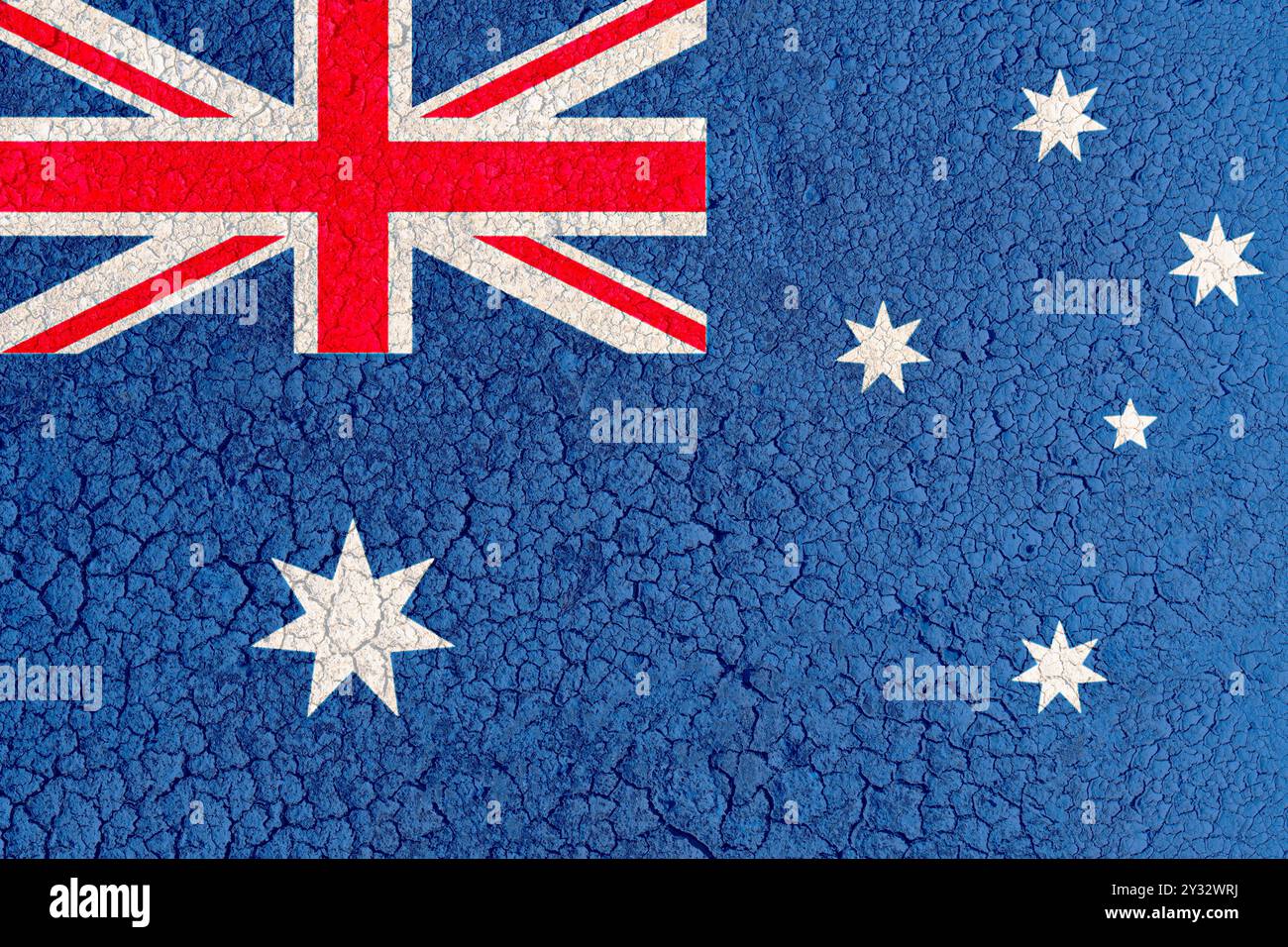 Cracked clay lake bed with Australian flag painted on it (close-up). Concept of climate change, drought and drying up of water bodies in Australia Stock Photo