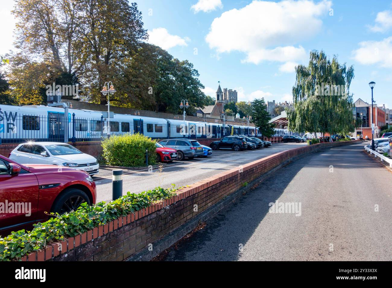 Walking through the car park at Windsor & Eton Riverside Railway Station, a train is seen waiting at the platform. Stock Photo