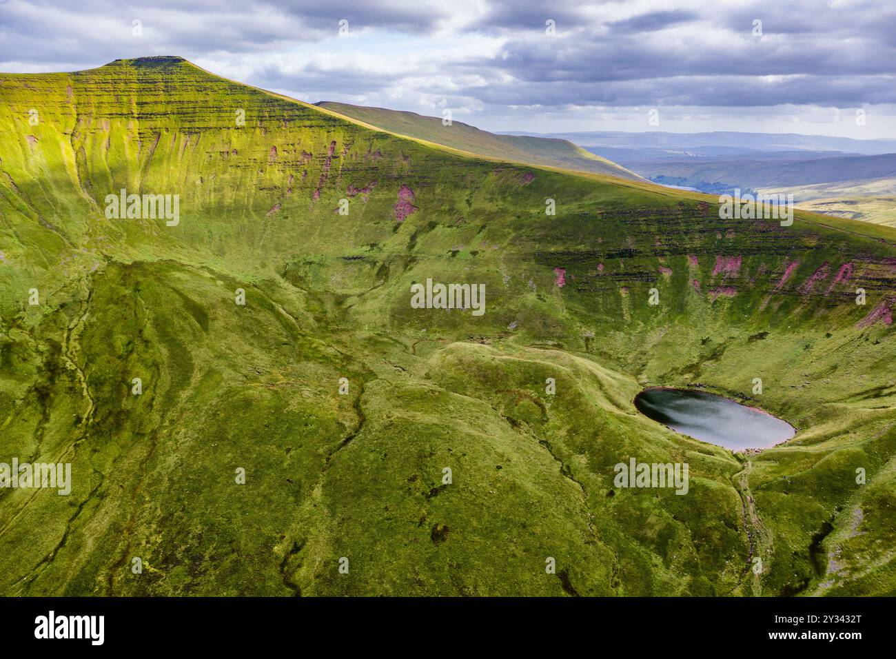 Aerial view of a small glacial lake beneath twin mountain peaks on a summers day Stock Photo