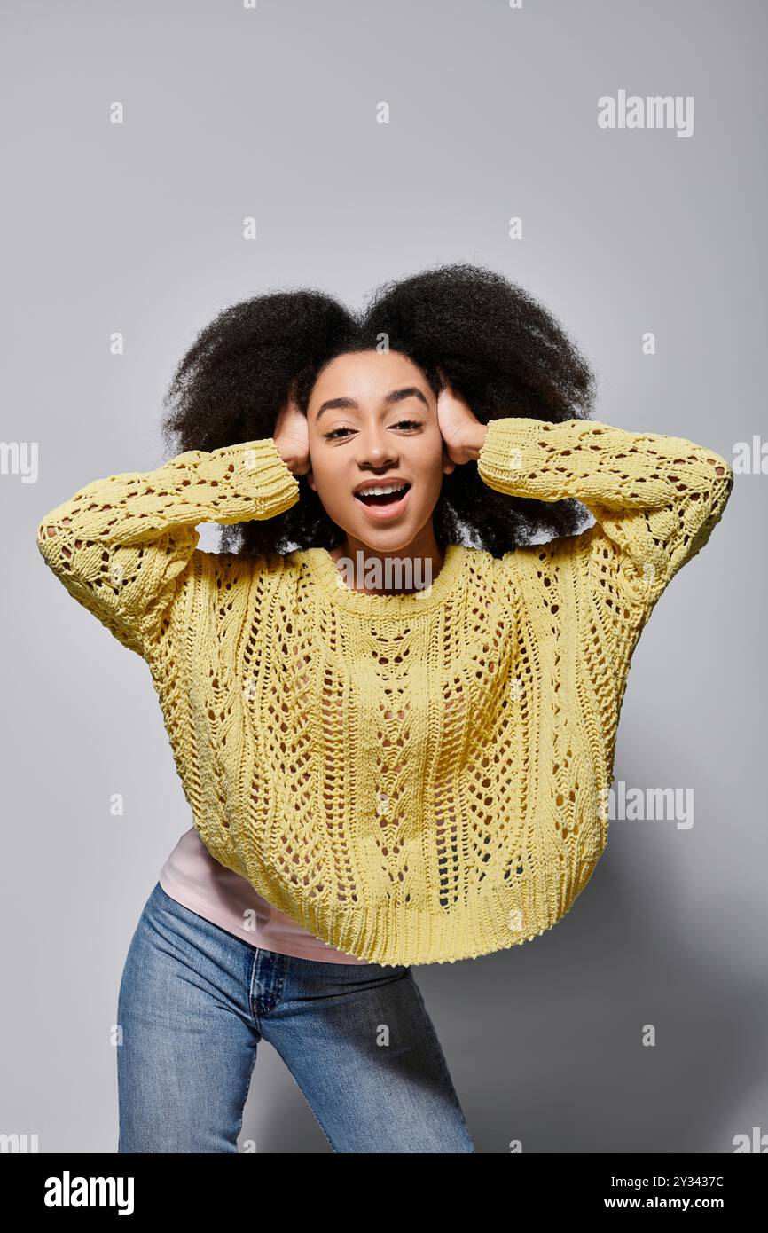 This vibrant young woman expresses joy, holding her curly hair in a ...