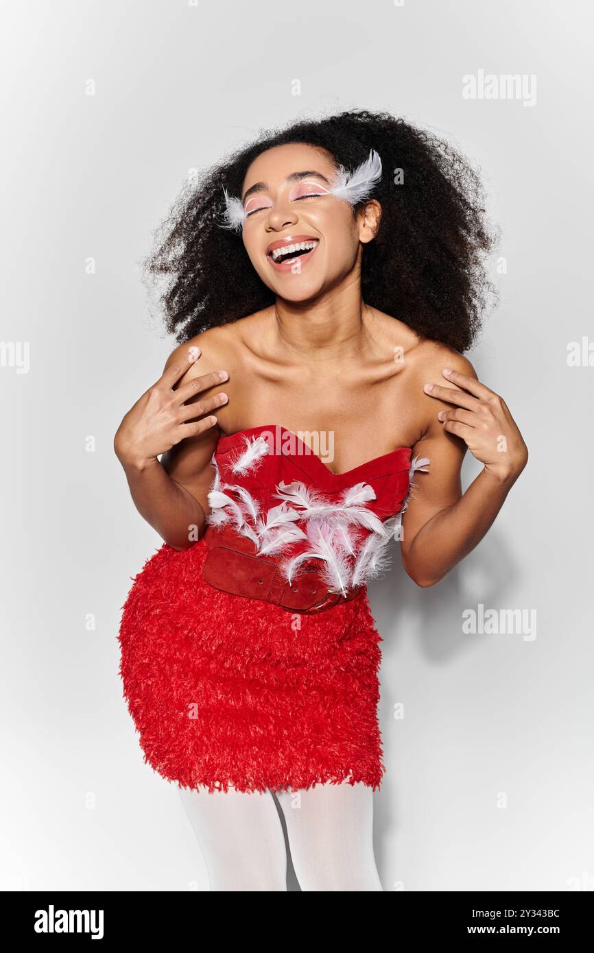 A cheerful young woman in a red feathered outfit poses playfully ...