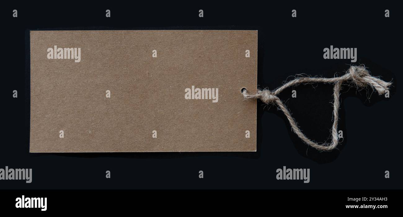 Blank brown tag with rustic thread string isolated on black background. Copy space. Stock Photo