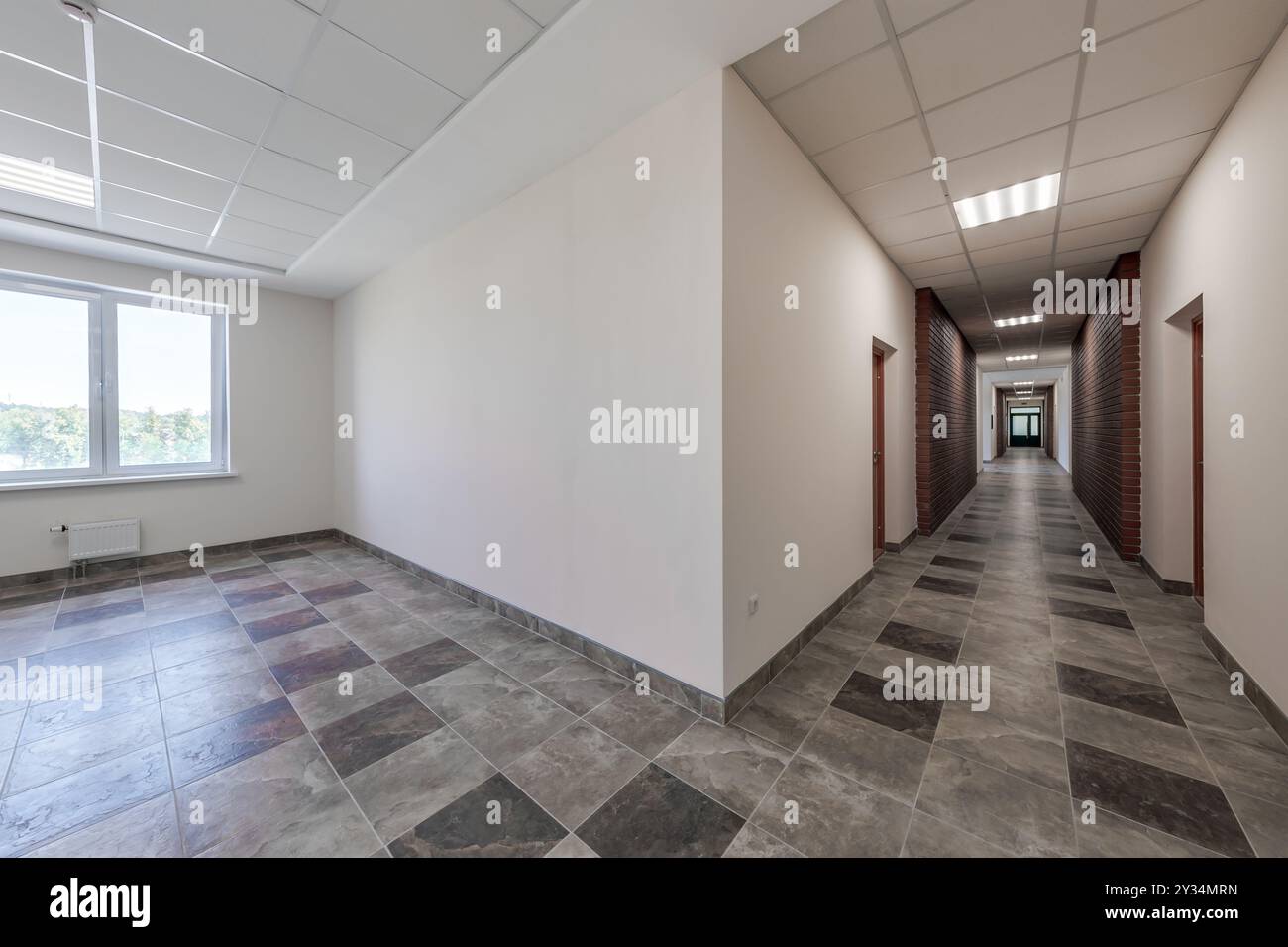 empty long corridor with red brick walls and doors in interior of modern apartments or office Stock Photo