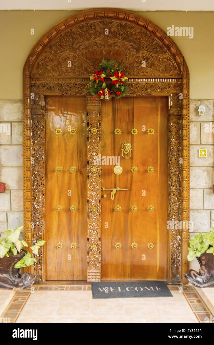 Indian-style wooden archway and entrance door with two windows and two flowerpot shoes in Nairobi city, Kenya, Africa Stock Photo