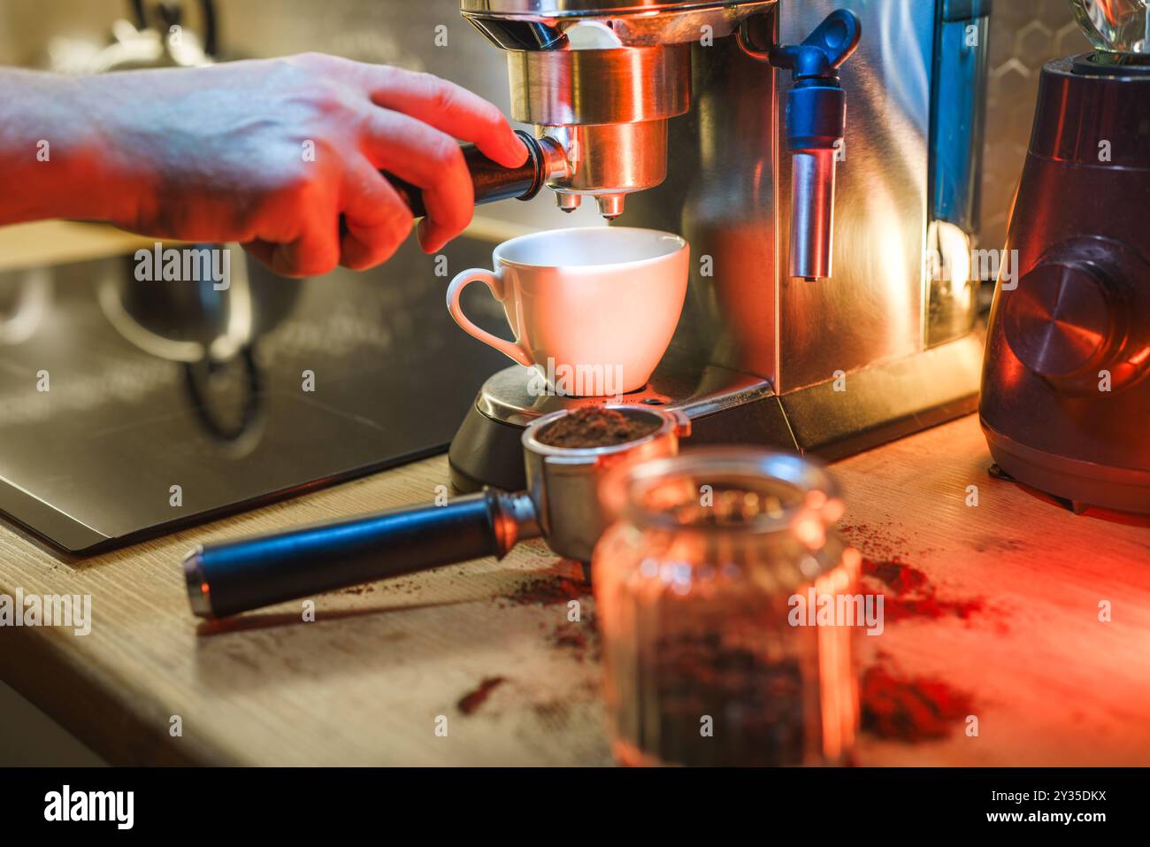 Barista operating an espresso machine. Home kitchen interior. Colorful lights. Stock Photo