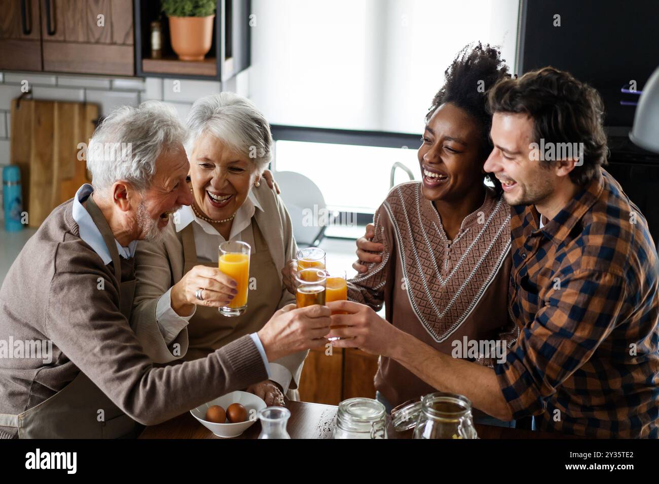 Multi generation multiethnic family having fun, talking around a festive kitchen table. Stock Photo