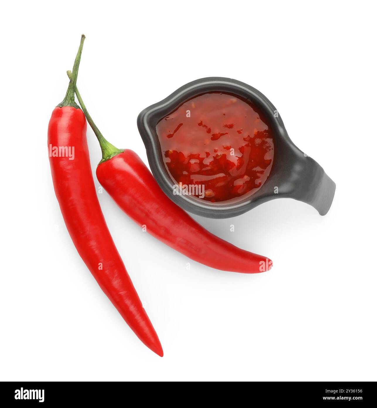 Hot chili sauce in gravy boat and peppers isolated on white, top view Stock Photo