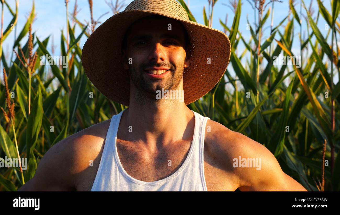 Happy smiling male farmer looks into camera standing near corn meadow ...
