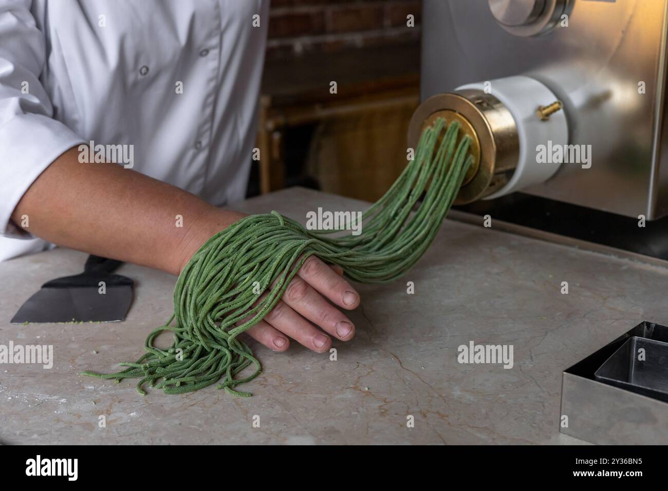 Chef Prepares Green Noodles Using A Pasta Machine In A Trendy Kitchen Chef prepares green noodles using a pasta machine in a trendy kitchen