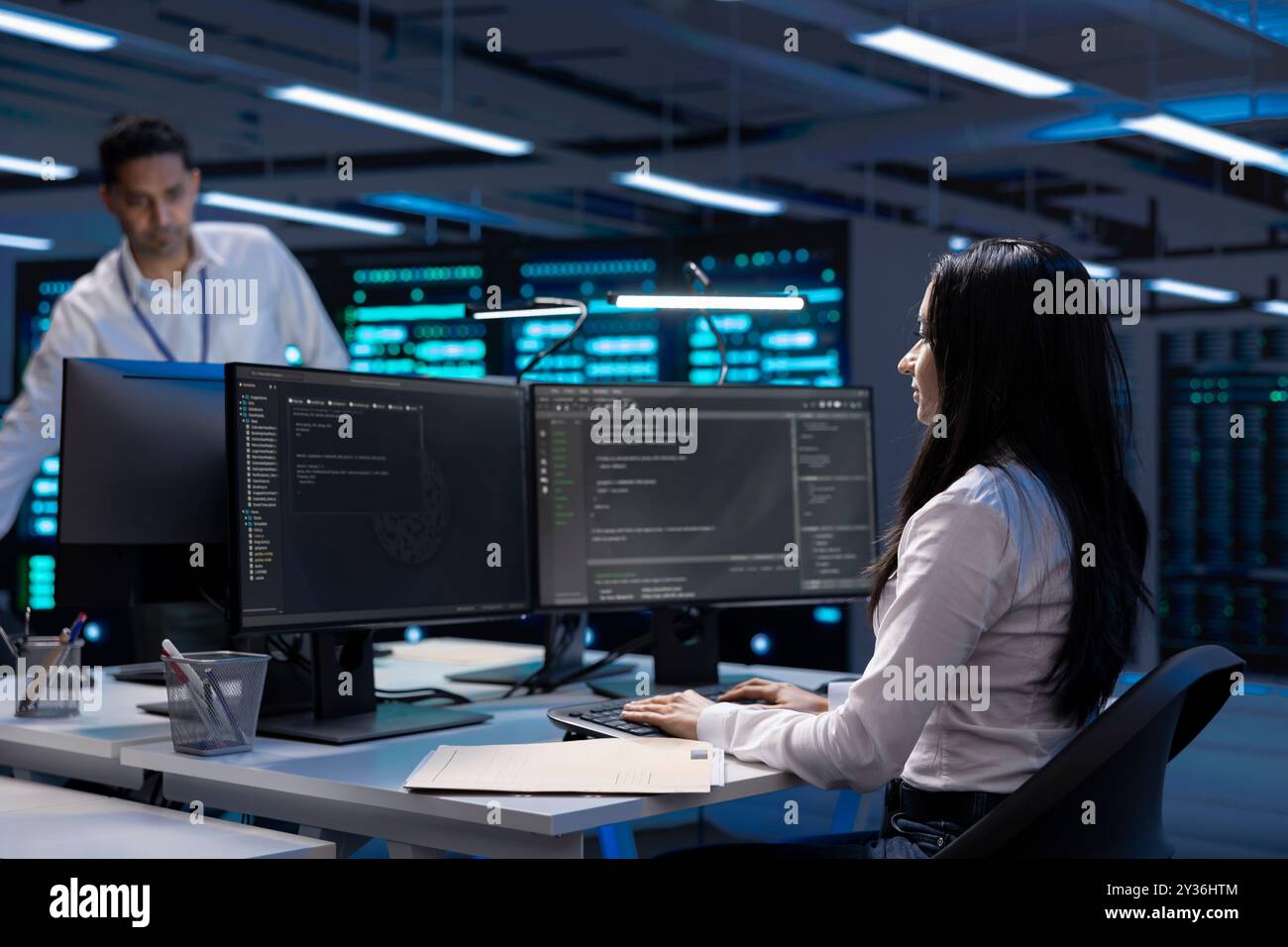 Software developer using computer, optimizing data center performance. Woman coding on PC, troubleshooting mainframes, ensuring optimal performance and minimizing downtime Stock Photo