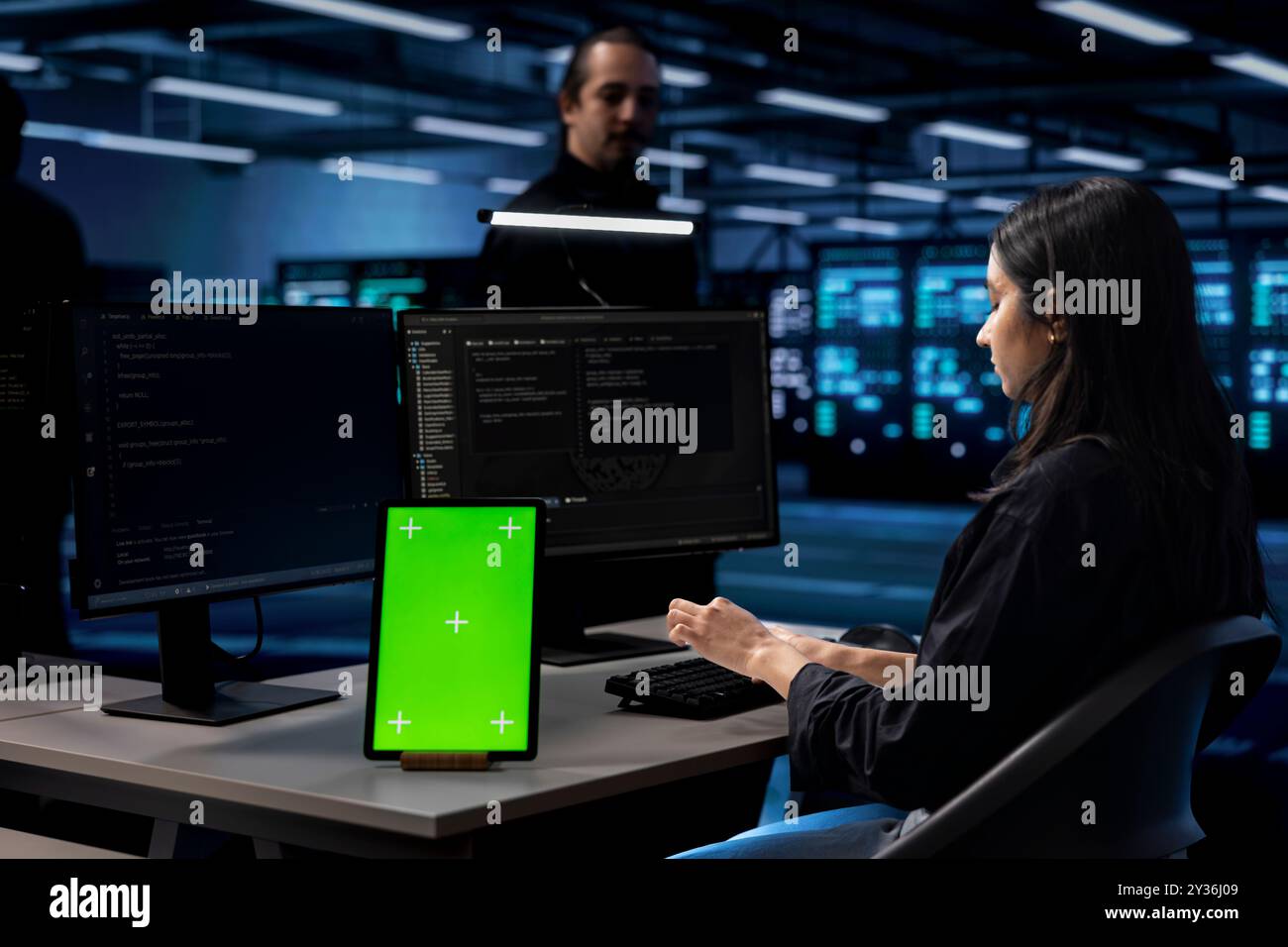 Engineer in data center uses isolated screen tablet to update systems, protecting servers from software vulnerabilities. IT expert uses chroma key device to look for errors affecting servers Stock Photo