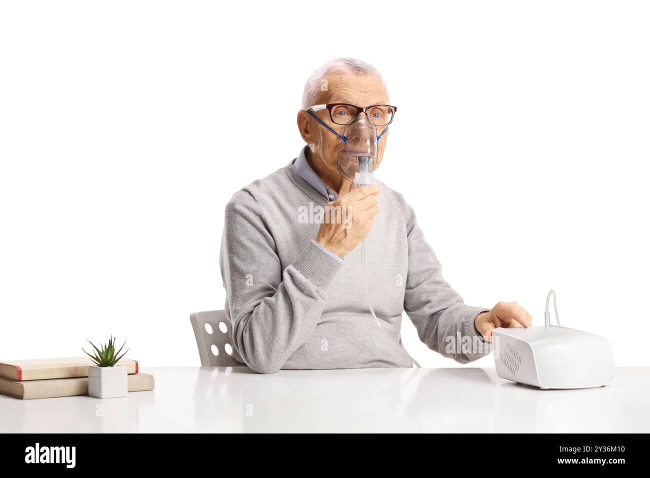 Senior sitting and using a nebulizer isolated on white background Stock Photo