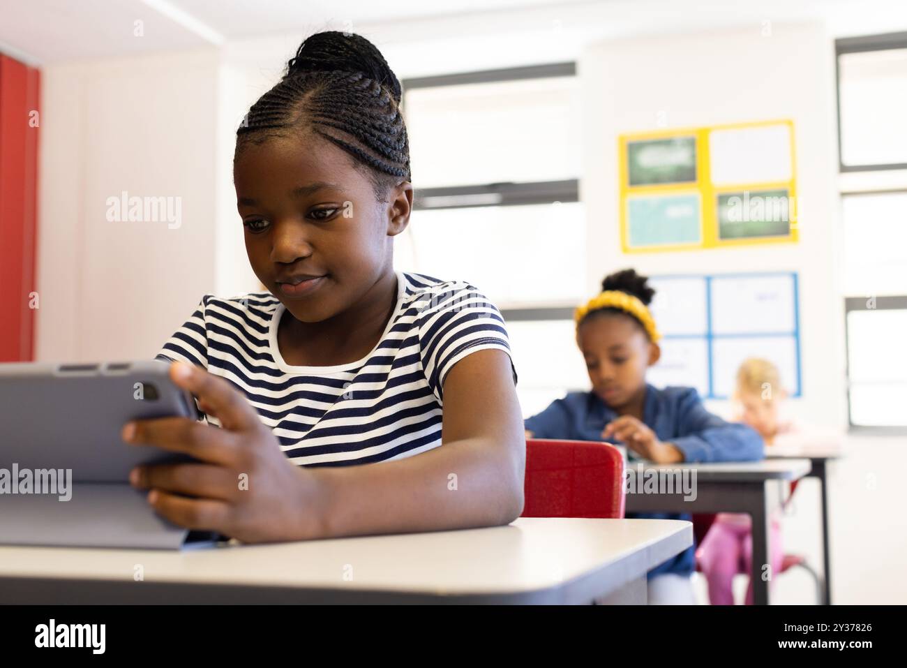 In school, african american girl using tablet at desk, focusing on ...