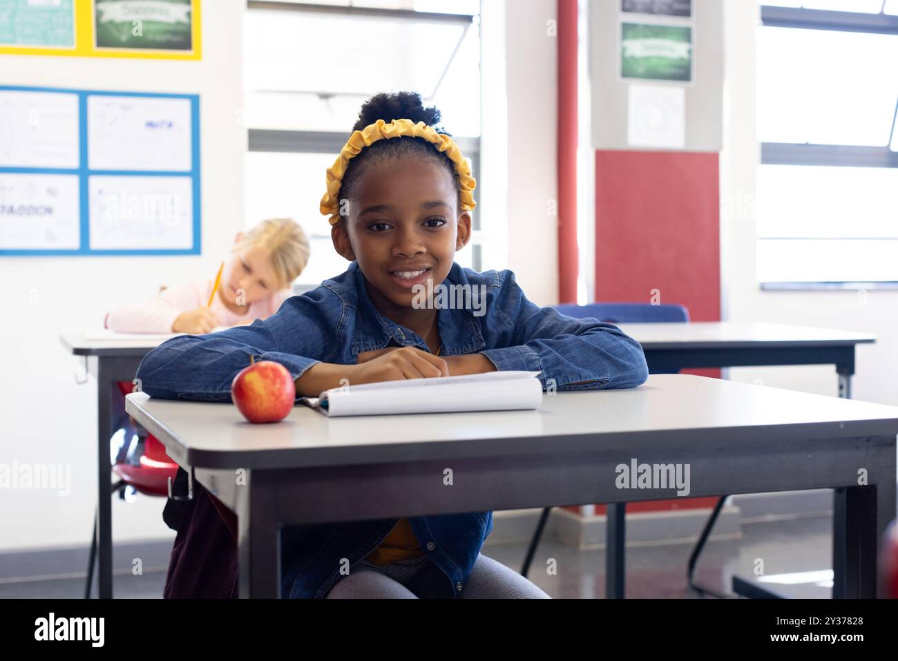In school, african american girl sitting at desk with notepad and apple ...