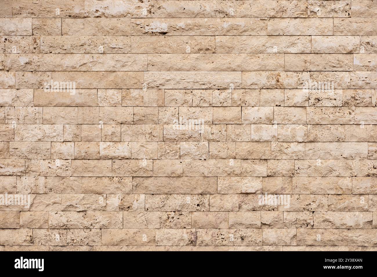 Textured beige stone wall with rectangular blocks in a modern architectural setting Stock Photo