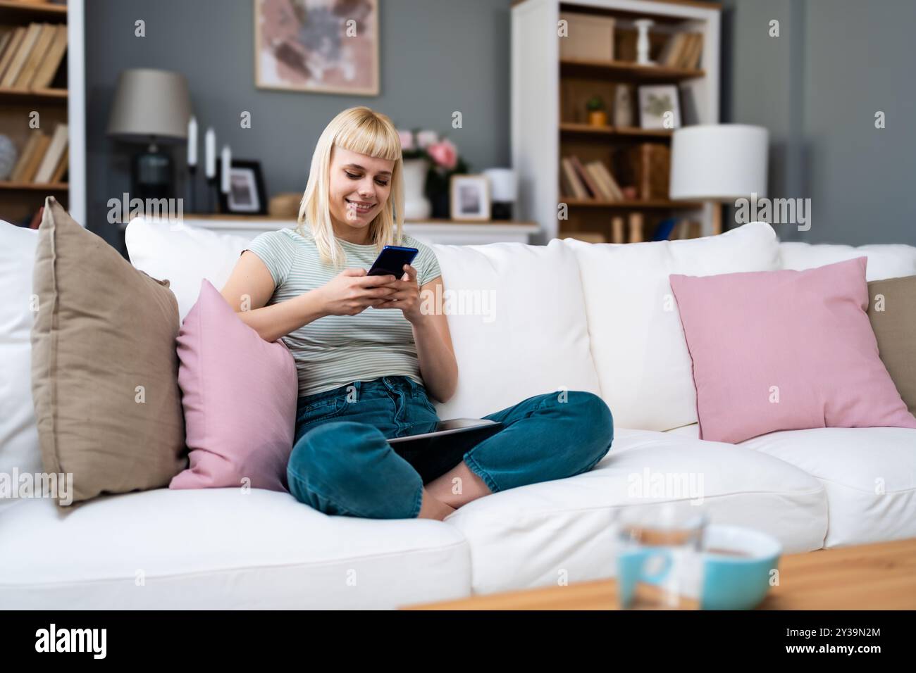 Happy relaxed young woman sitting on couch using phone, smiling lady ...