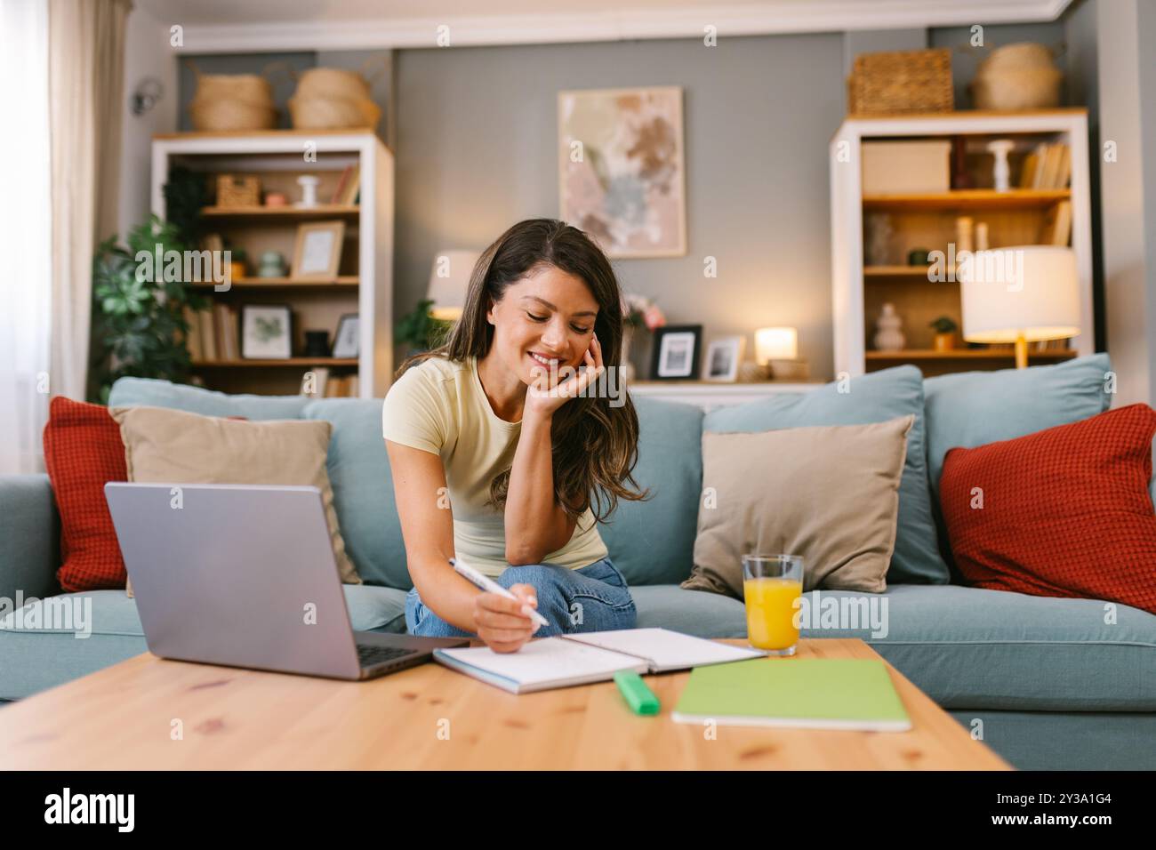 Happy woman working at home and taking notes Stock Photo
