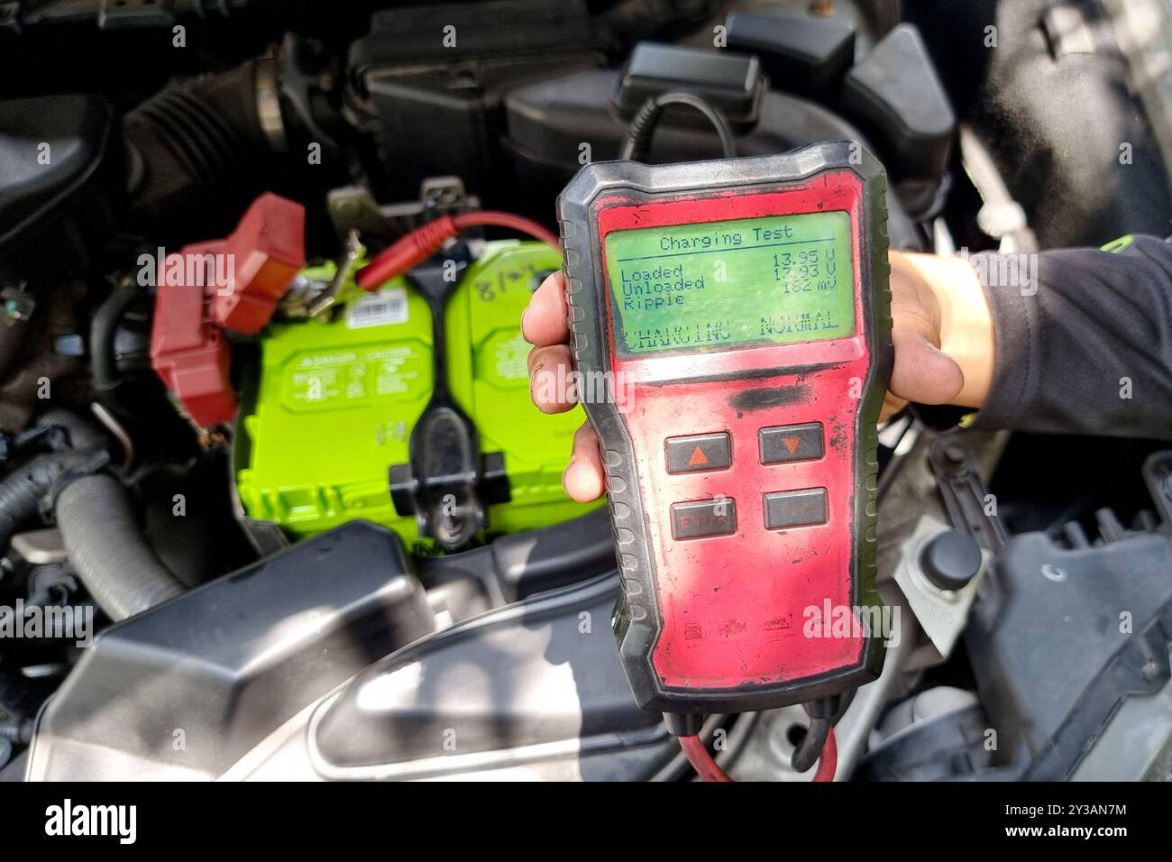 Technician diagnosing health of automobile alternator with instrument ...