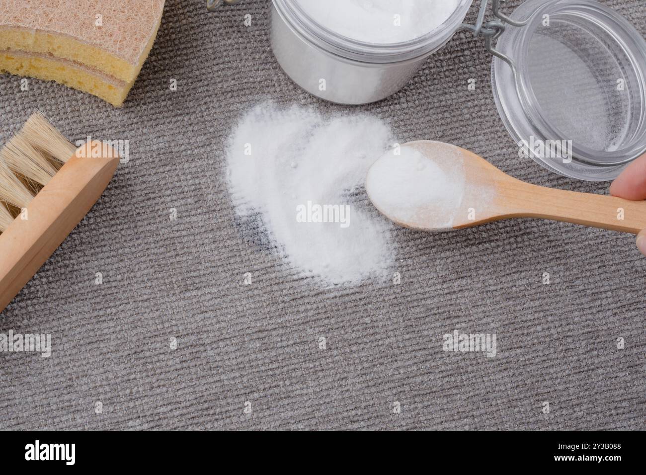 A woman's hand using natural ingredients baking soda to remove ink stains on gray textured upholstery of a sofa or carpet. top view. High quality phot Stock Photo