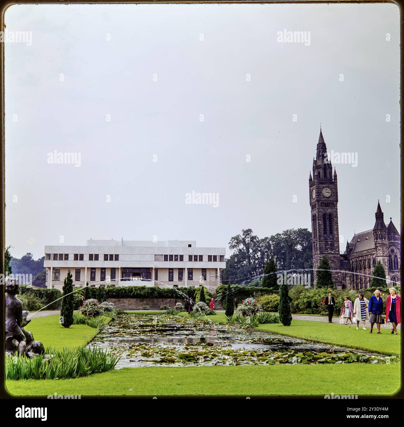 Eaton Hall, Eaton and Eccleston, Cheshire West and Chester, 1973. General view of Eaton Hall in the final stages of its construction from the east with a formal pond in the foreground and showing Eaton Chapel to the north. Since the first substantial house on the site, built in the 1670s, Eaton Hall has undergone a succession of demolitions, rebuildings and remodellings. In the 1960s the Victorian house, suffering from dry rot, was demolished and construction of this iteration of the hall began in 1971. Rectangular, flat-roofed and faced with white travertine the new building was considered un Stock Photo