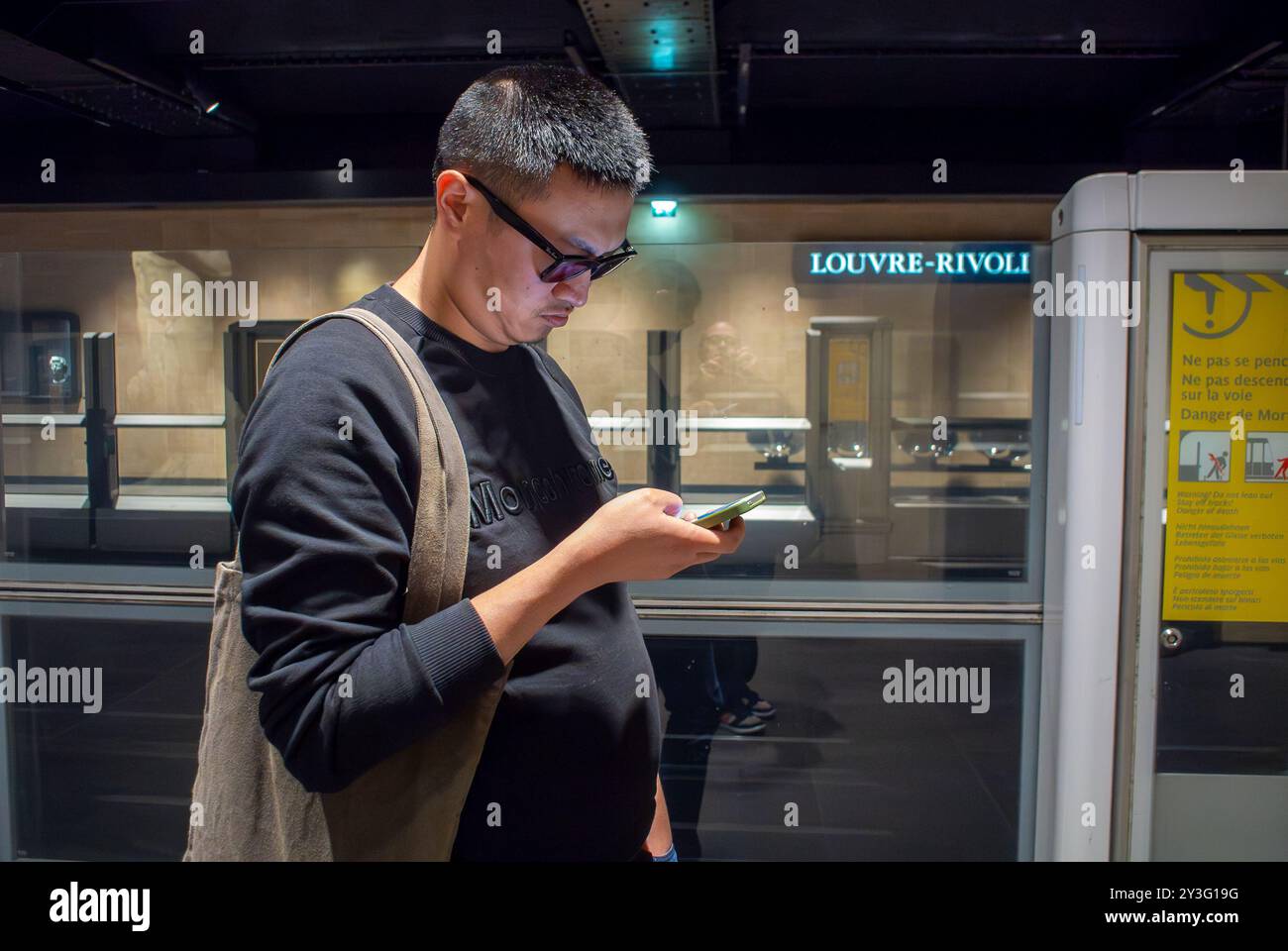 Paris, France, Chinese Man Standing on Platform, Inside Metro Station, Louvre-Rivoli, RATP Line 1, Paris, France, People Traveling, Smart Phone Stock Photo