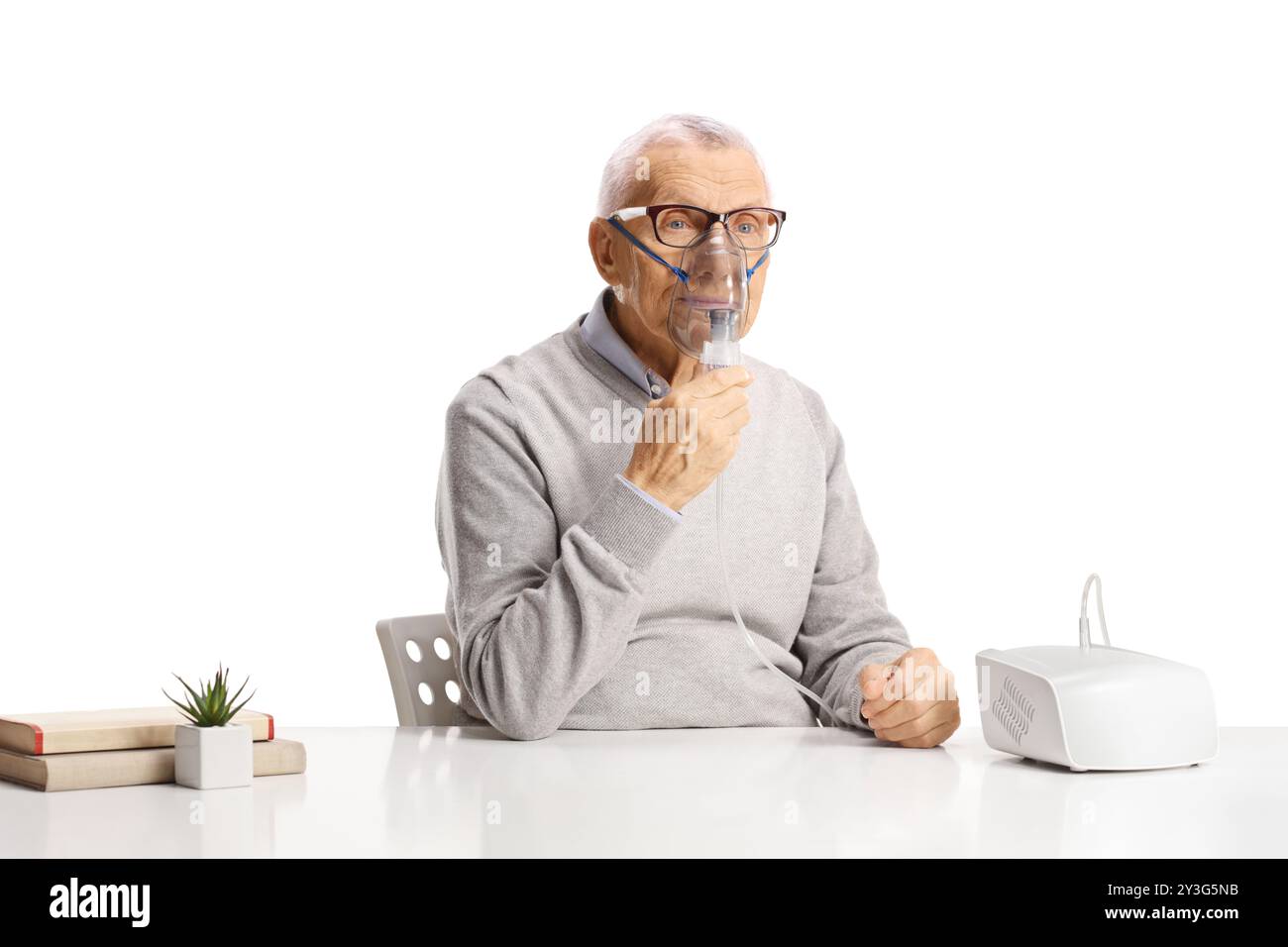 Senior man sitting and using a nebulizer isolated on white background Stock Photo