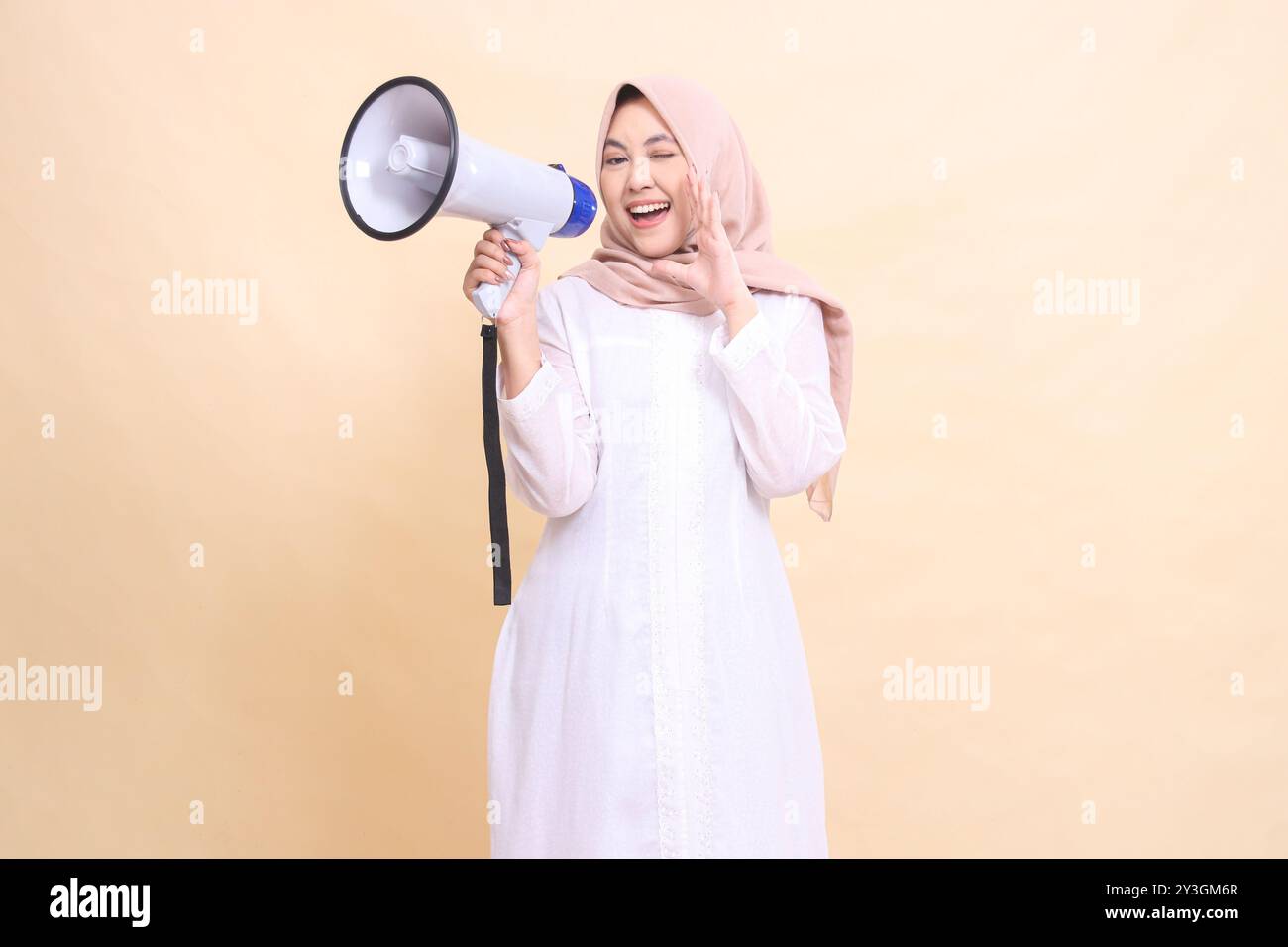 Asian Muslim woman wearing a hijab at the camera shouts cheerfully ...