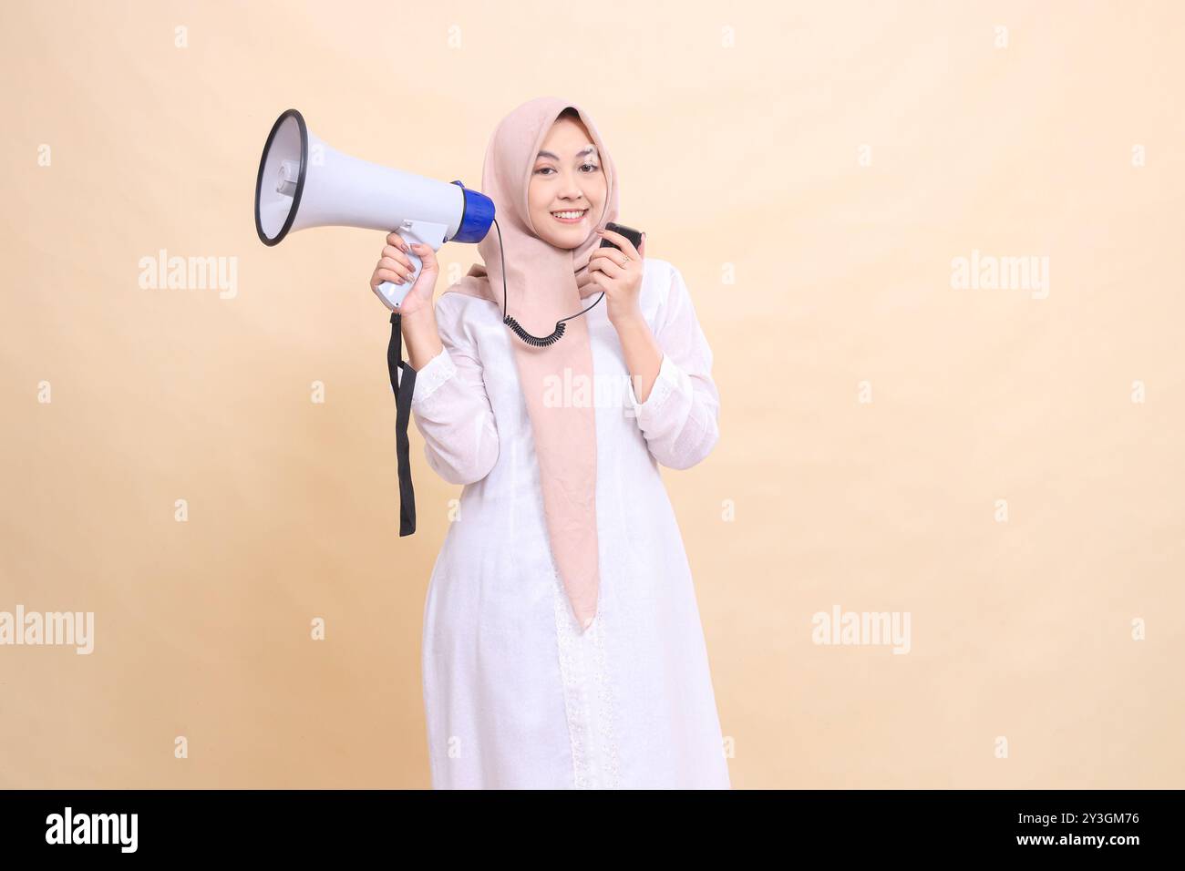 Asian Muslim woman wearing a hijab at the camera shouts, smiles, holds ...