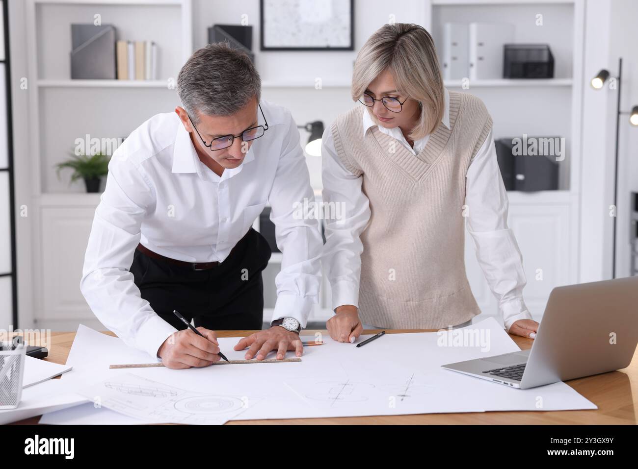 Architects making engineering drawing at wooden table in office Stock Photo