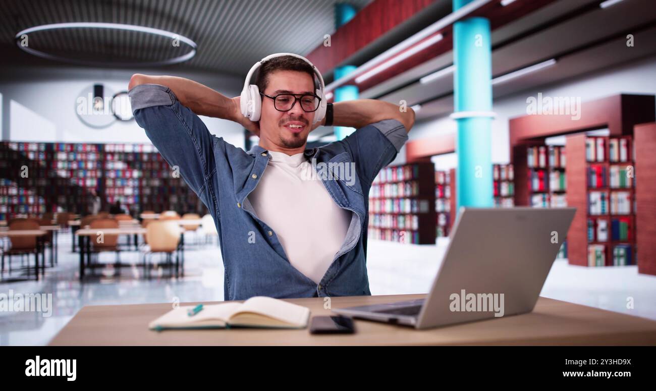 Hispanic Man Relaxing At Library While Using Laptop. Study Break Stock Photo