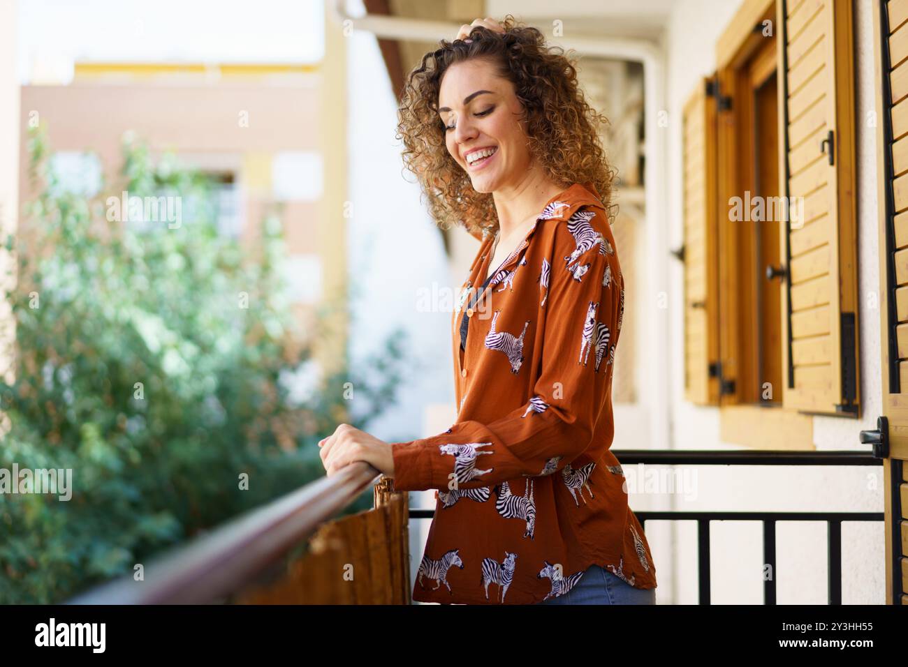 Cheerful young woman standing on balcony Stock Photo