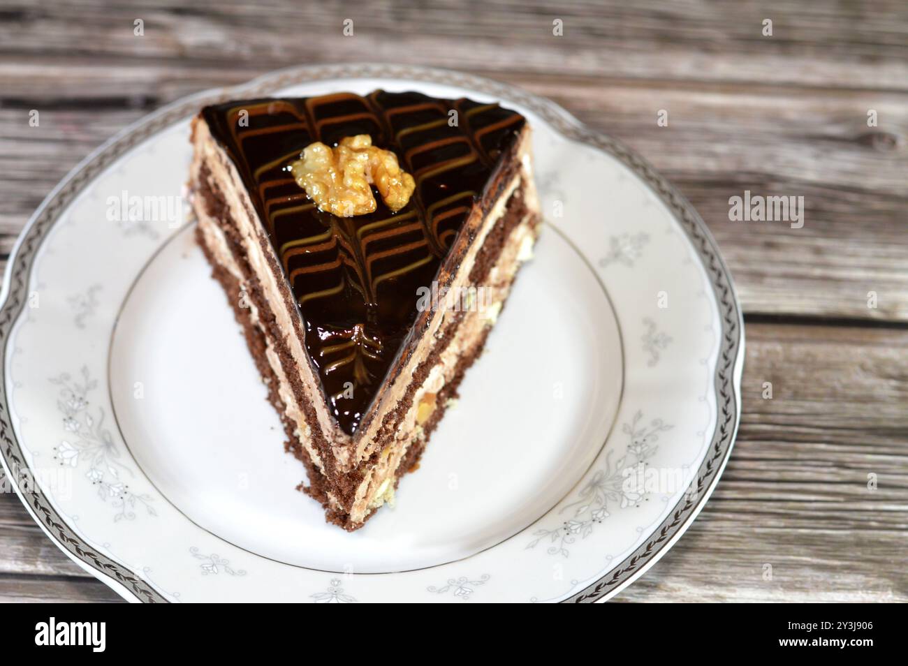 chocolate triangular spongy cake piece filled and topped with walnut ...