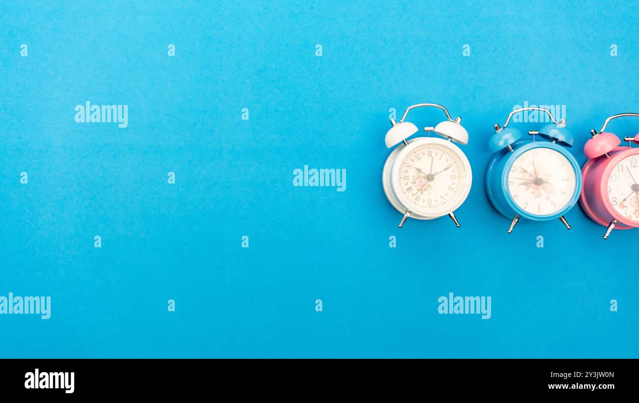 Flat lay retro beautiful new alarm clock on blue paper pastel color ...