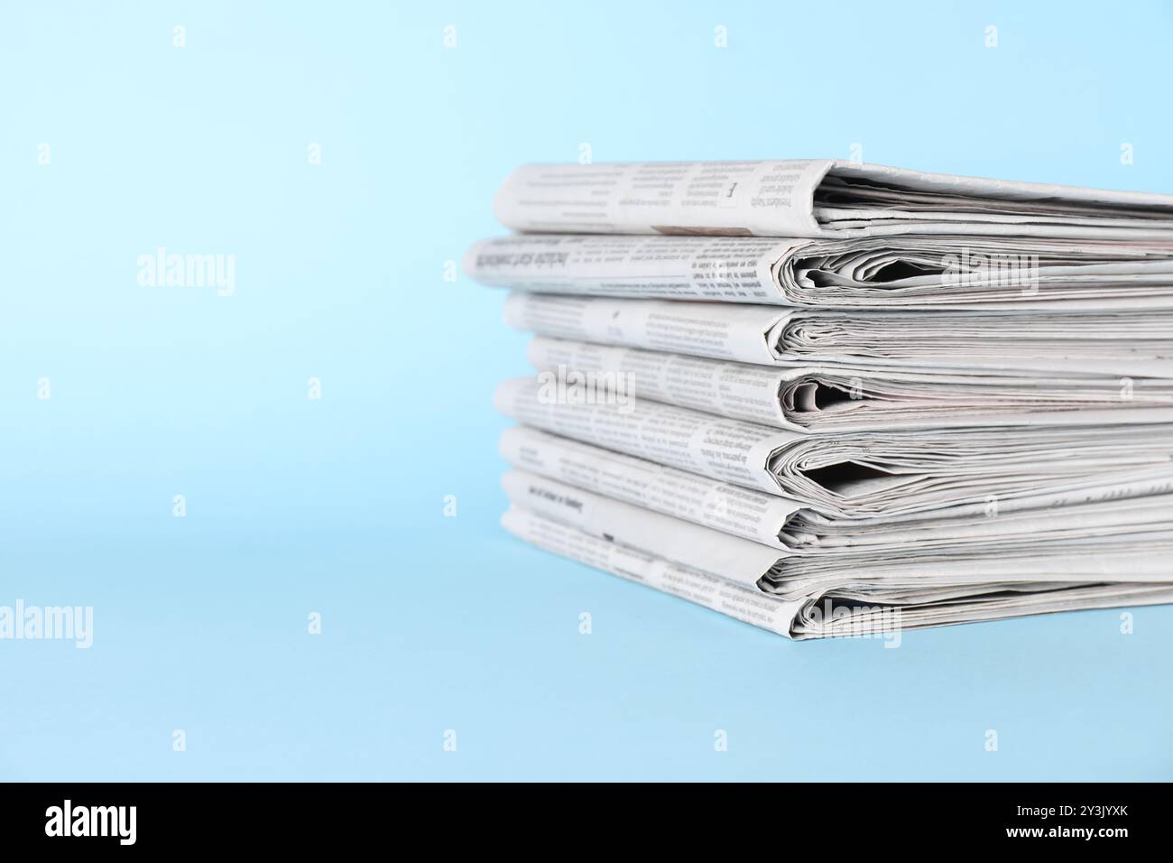 Stack of newspapers on light blue background, space for text Stock Photo