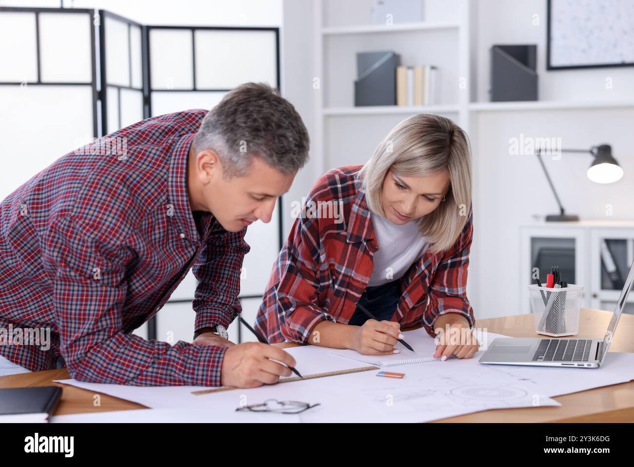 Architects making engineering drawing at wooden table in office Stock Photo