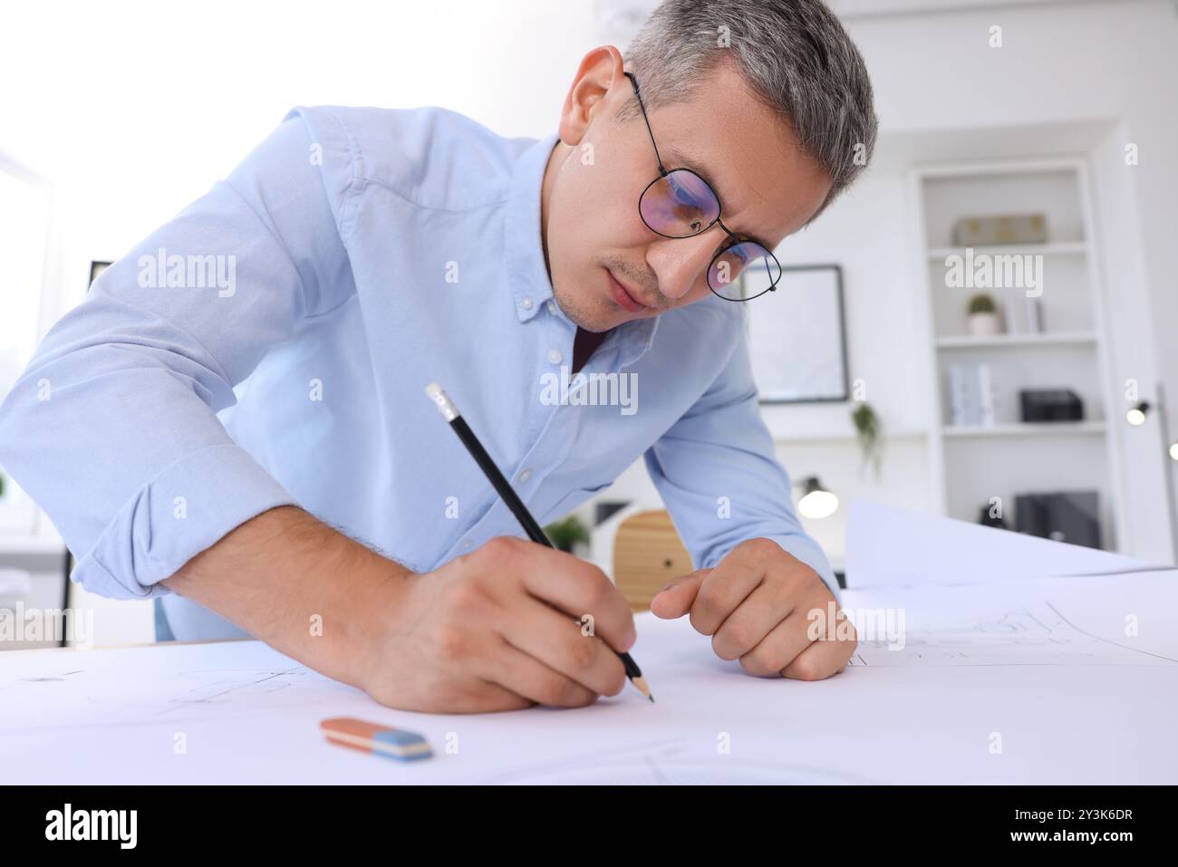 Architect making engineering drawing at table in office, low angle view Stock Photo